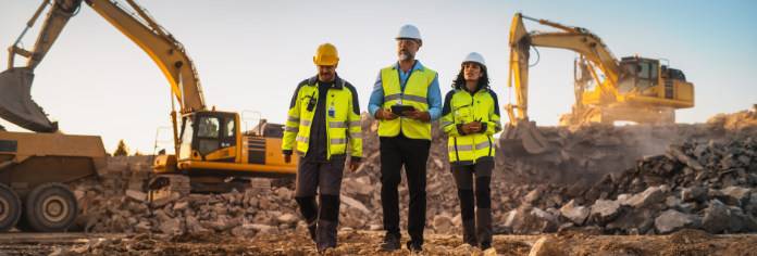 Drei verantwortliche Bautechniker laufen über eine Baustelle