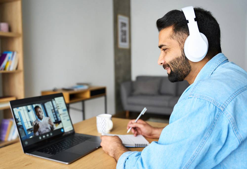 Mann hört Webkonferenz am Notebook zu